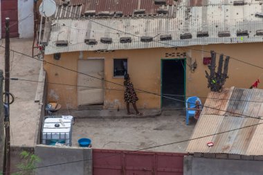 Luanda / Angola - 12 / 07 / 2020: Luanda şehrinin orta kesimindeki yoksul mahallelerde, Angola 'da musseques adı verilen fakir varoşlarda, pencerelerin önündeki avluda, başka bir kadınla konuşan Afrikalı bir kadının havadan görünüşü