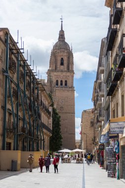 Salamanca / İspanya - 05: 12 2021: Salamanca şehir merkezindeki Belediye Başkanı caddesinde bina mağazaları ve yürüyen insanlar, arka plan olarak Salamanca katedrali kulesi binası