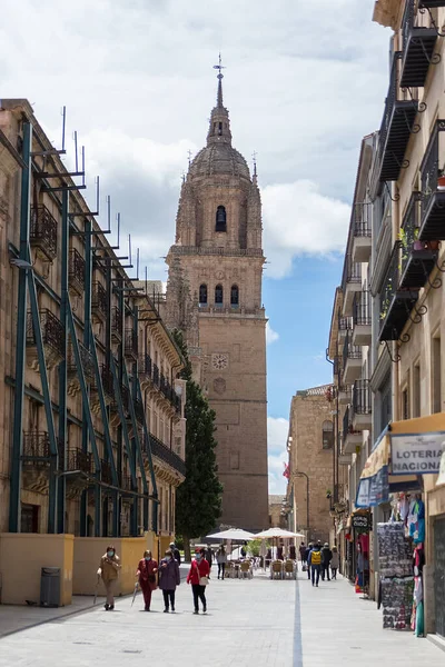 Salamanca / İspanya - 05: 12 2021: Salamanca şehir merkezindeki Belediye Başkanı caddesinde bina mağazaları ve yürüyen insanlar, arka plan olarak Salamanca katedrali kulesi binası