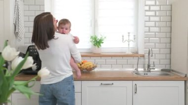 Anne ve bebek beyaz bir mutfakta.