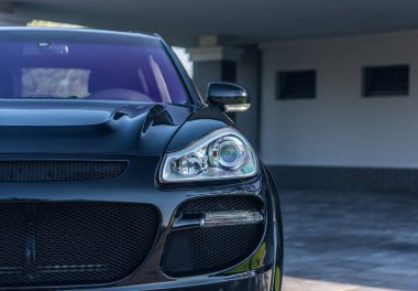 Modern villanın dışında park etmiş siyah bir SUV. Kapalı garaj, asfaltlı garaj yolu, mimari çizgiler. Ön profili ince çizilmiş.