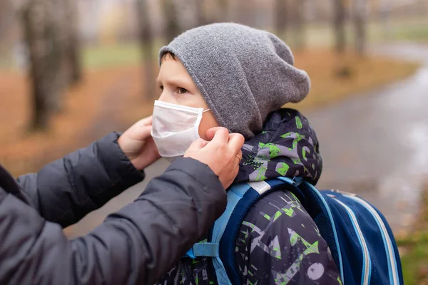 the Mom adjusts the mask to the child on the street