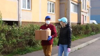 Gönüllü sokakta bir kutu yiyecek taşıyor.