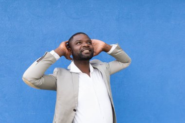 Mavi arka planda telefonu olan mutlu Afrikalı Amerikalı.