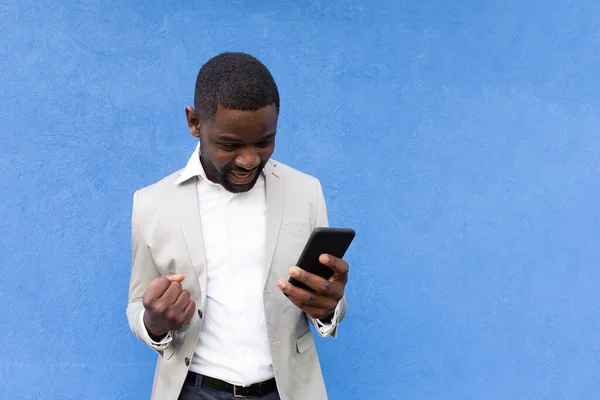 the happy African American with phone on blue background