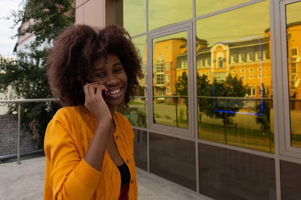 the beautiful and happy African American on the street with her phone