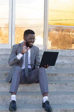 Sokakta dizüstü bilgisayarlı, serbest çalışan mutlu Afrikalı Amerikalı.