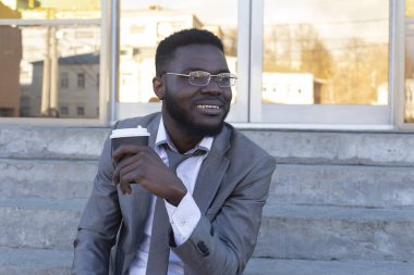 Gülümseyen bir Afrikalı Amerikalı arkadaşlarına telefonda mesaj yazıyor..