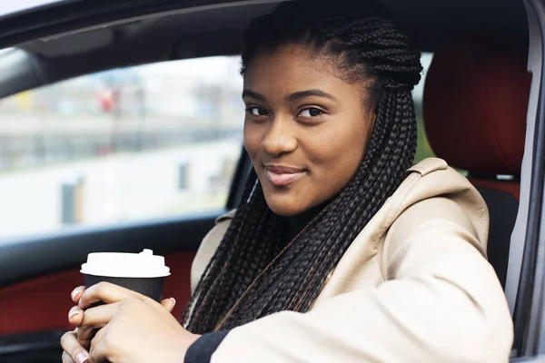 the happy african american woman in car with coffee