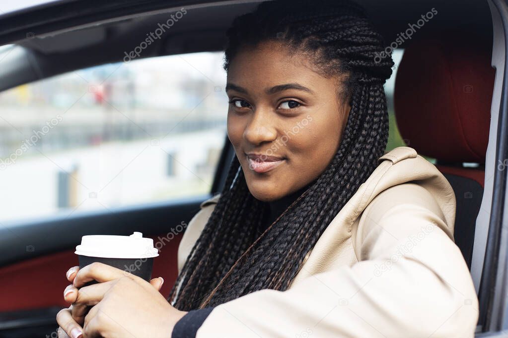 the happy african american woman in car with coffee