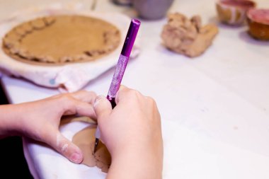 Kil atölyesindeki kız kille çalışıyor.