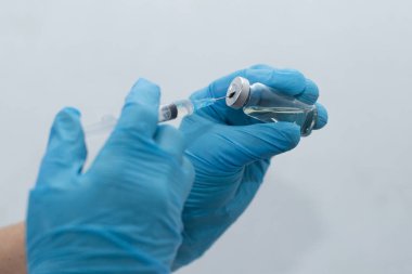 Kadınların elleri tıbbi eldivenlerde, aşılarda.