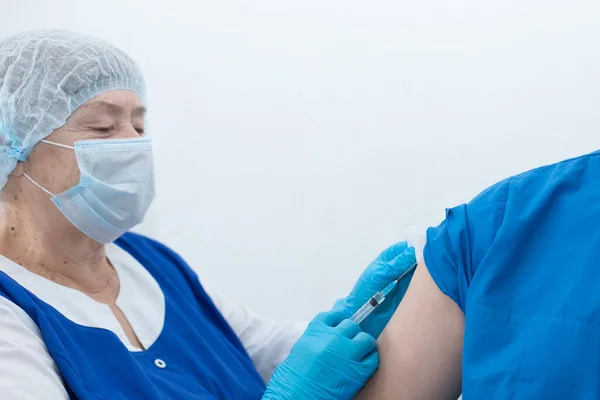 An elderly nurse gives injection, vaccinatio
