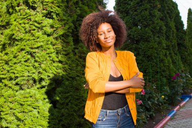 Mutlu ve genç Afrikalı Amerikalı kadın sokakta yürüyor.