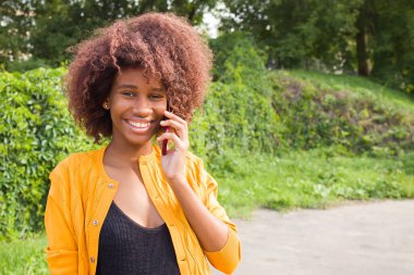 Sokakta telefonla konuşan mutlu Afrikalı Amerikalı kadın.