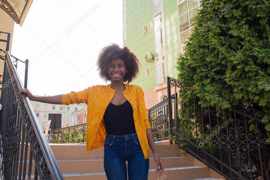 happy and young African American woman walks down the street