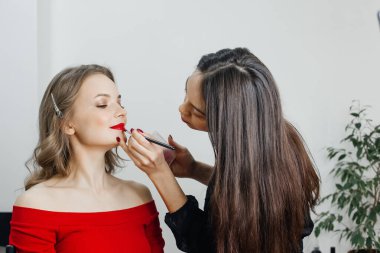 Usta güzellik salonunda güzel bir sarışın makyajı yapıyor.