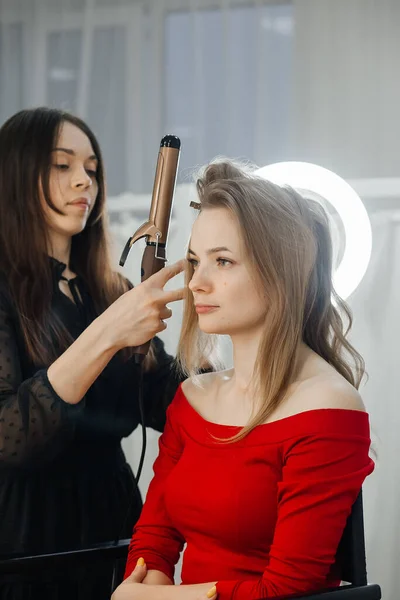 the master makes a hairstyle for a girl, beautiful curls