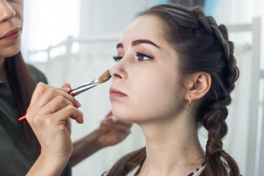 Usta güzellik salonunda güzel bir sarışın makyajı yapıyor.