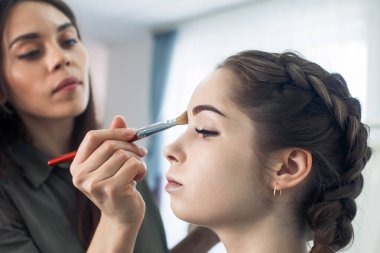 Usta güzellik salonunda güzel bir sarışın makyajı yapıyor.