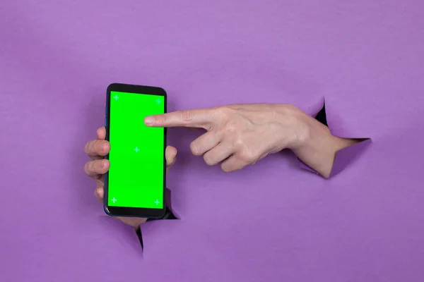 phone with green screen in hand on purple background, hand gesture, through the background hand slot.