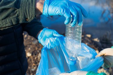 Gönüllüler poşetlerde plastik şişeler, yakın çekim eller, ekoloji konsepti ve dünyanın korunması.
