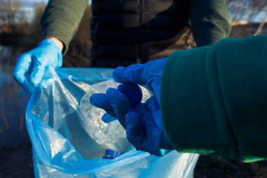 Gönüllüler poşetlerde plastik şişeler, yakın çekim eller, ekoloji konsepti ve dünyanın korunması.