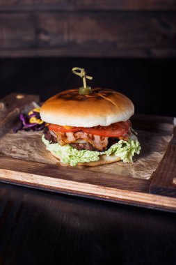 Lokantadaki ahşap tepside, karanlık bir arka planda çizburger..