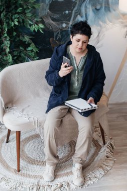 Kısa saçlı bir kız, deftere yazıyor ve evden uzaktan arama yapıyor..