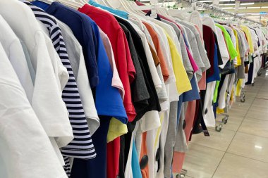 Üst üste farklı renklerde tişörtler. Renkli kadın tişörtleri. Pastel renkli tişörtler. Yazın perakende mağazasında askılarda asılı..