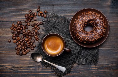 Kırsal ahşap arka planda, espresso ve çikolata kaplı çöreklerle nefis bir kahvaltı.