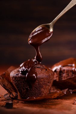 Eritilmiş siyah çikolata çikolatalı kekin üzerine dökülür. Koyu kahverengi kompozisyon ve arka plan. Durgun hayat