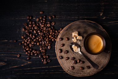 Kırsal ahşap arka planda, üst manzaralı, kavrulmuş kahve çekirdekleri, esmer şeker ve bir fincan espresso.