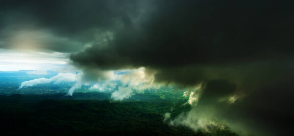 Motion blur. Dramatic dark storm clouds over a green forest and mountains. Environment, Climate change concepts.