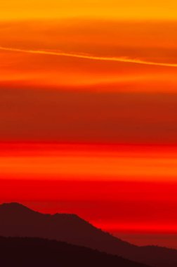 Gün batımı gökyüzünde dramatik bulutlar dağların üzerinde, kızıl gökyüzünde sihirli dalgalar bulutlar. Gökyüzüne odaklan..