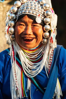 Chiang Rai, Tayland - 3 Aralık 2014: Geleneksel giysiler içinde Akha el yapımı, aksesuar, kolye, gümüş ve boncuk satan yaşlı bir Akha kadını. Doi Mae Salong.