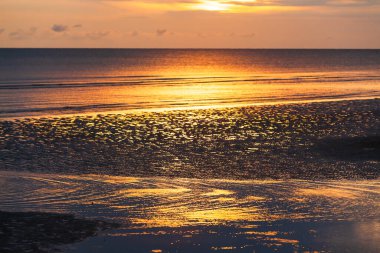 Gün batımında sakin bir yaz plajı. Tropikal bir sahil ve okyanus dalgalarında dramatik bir günbatımı yansıması. Chanthaburi, Tayland. Turizm, tatil, tatil kavramları. Sahile odaklan..