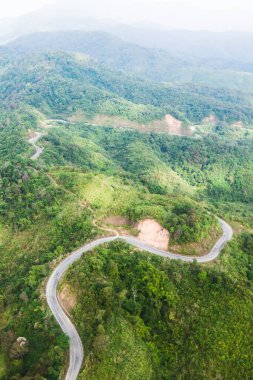 Tayland-Myanmar sınırı yakınlarındaki eğri dağların hava manzarası. Dağların yolu yeşil ormanlarla çevrili. Geliştirme, ulaşım kavramları.