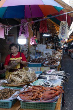 Phetchaburi, Tayland - 2 Ocak 2026: Islak pazarda günlük hayat, çeşitli tuzlu balık satan bir satıcı. Mueang Phetchaburi.