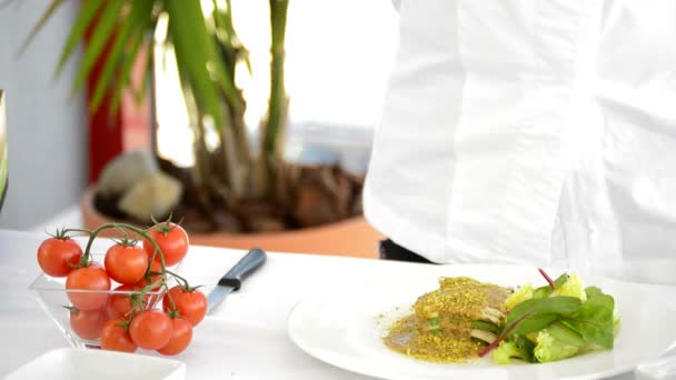 Hands of chef cutting and adding a cherry tomato to a recipe with salad, avocado an sauce — Stock Video