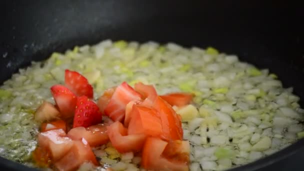 Кулинария в горячей сковороде с манго, помидорами, клубникой и луком — стоковое видео