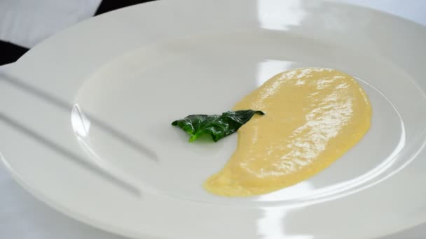 Kocken att lägga spenat blad på en tallrik med senap sås på ett öppet kök — Stockvideo