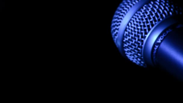 Microphone avec lumière bleue tournant sur fond noir — Video