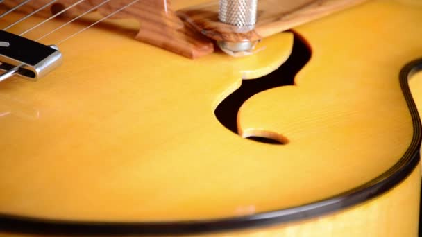 Detail of bridge, strings and efes of a jazz electric guitar rotating — Stock Video