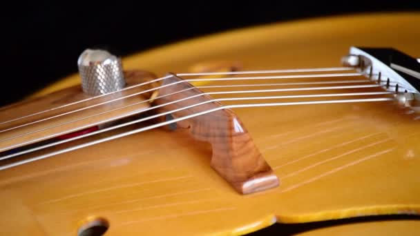 Détail du pont, cordes et efe du corps d'une guitare jazz électrique classique tournant en arrière-plan noir 