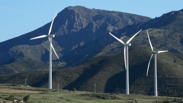 Пейзаж движения ветряных турбин, поля и горы с голубым небом — стоковое видео
