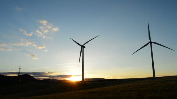 Windkraftanlage dreht sich bei Sonnenuntergang am bewölkten Tag auf dem Feld — Stockvideo