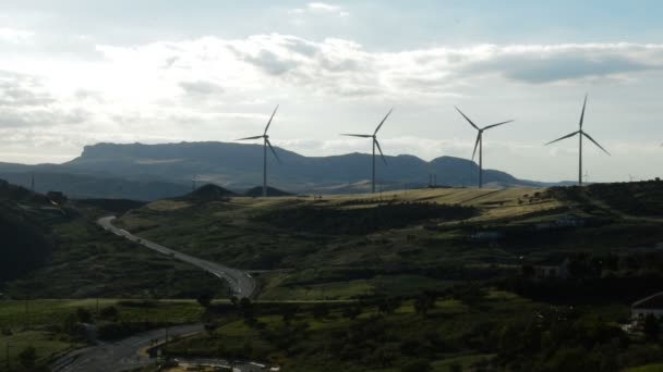 Turbinas eólicas energía en movimiento en la montaña juntos una carretera en día nublado — Vídeos de Stock