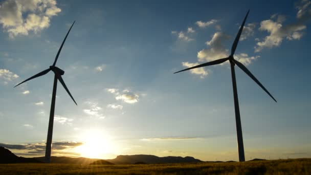 Turbina wiatrowa, obracając go w pole zachód słońca — Wideo stockowe