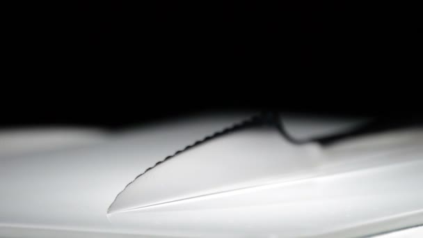 Металлический нож вращается на белом основании на черном фоне — стоковое видео